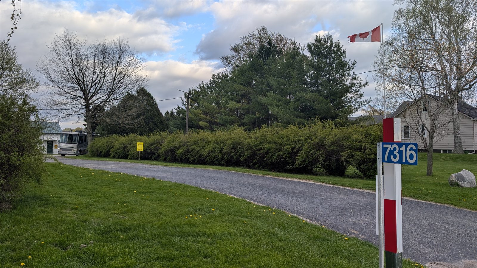 The blue 7316 address marker and Canadian flag at the entrance of Moro Storage on Sunset Road